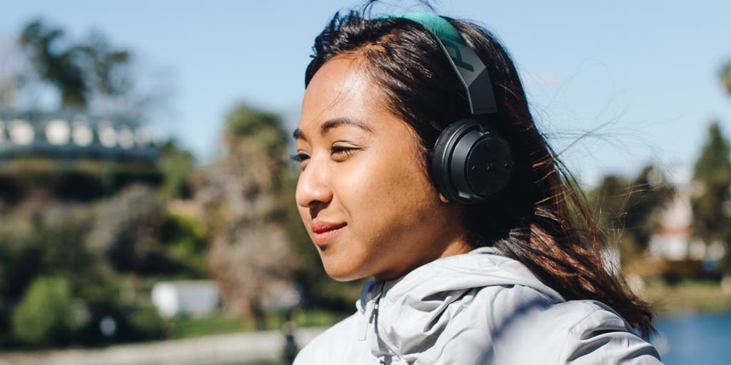 A person wearing over-ear headphones while standing outside on a sunny day.